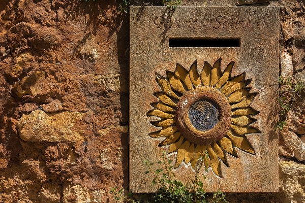 steinerner Briefkasten mit gravierter Sonnenblume, Roussillon - Provence, Frankreich